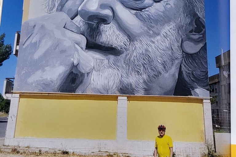 In bici sotto il murale di Gino Strada