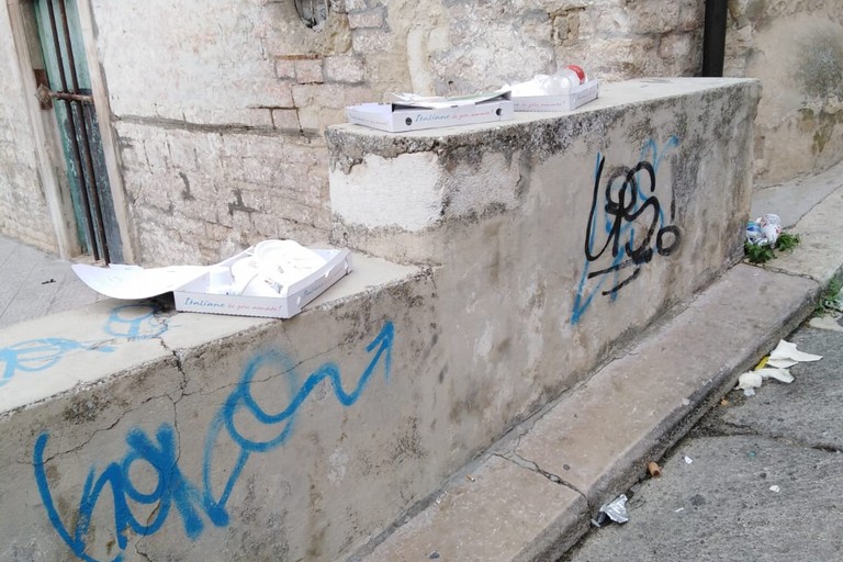 Cartoni di pizza abbandonati di fronte alla chiesetta di San Lorenzo