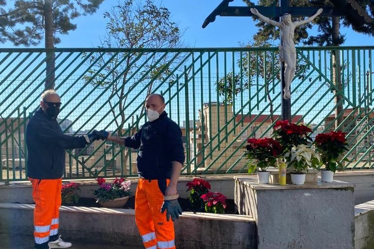 Due concittadini andriesi adornano il Crocifisso nei pressi del Cimitero